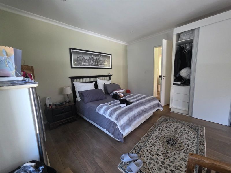 A well-maintained bedroom featuring laminate flooring, neutral wall tones, and a functional built-in wardrobe with sliding doors.