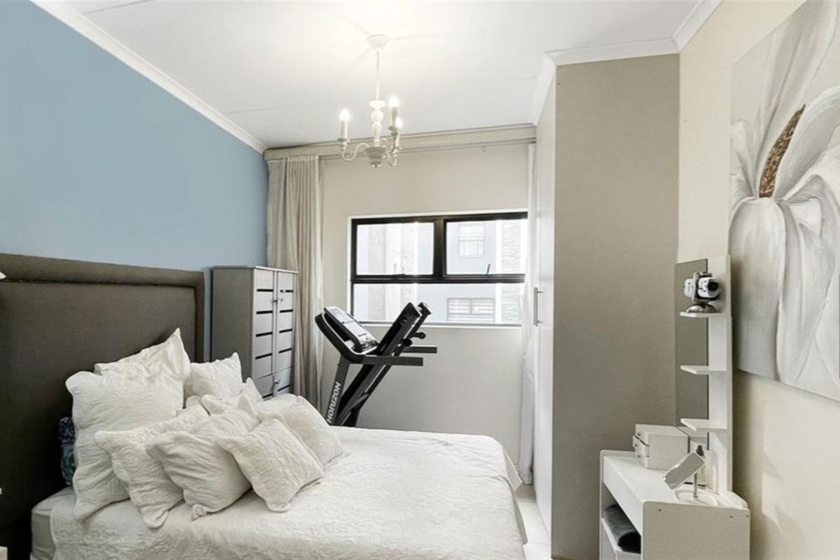 A well-maintained bedroom featuring built-in cupboards, a large window for natural light, and classic crown molding.
