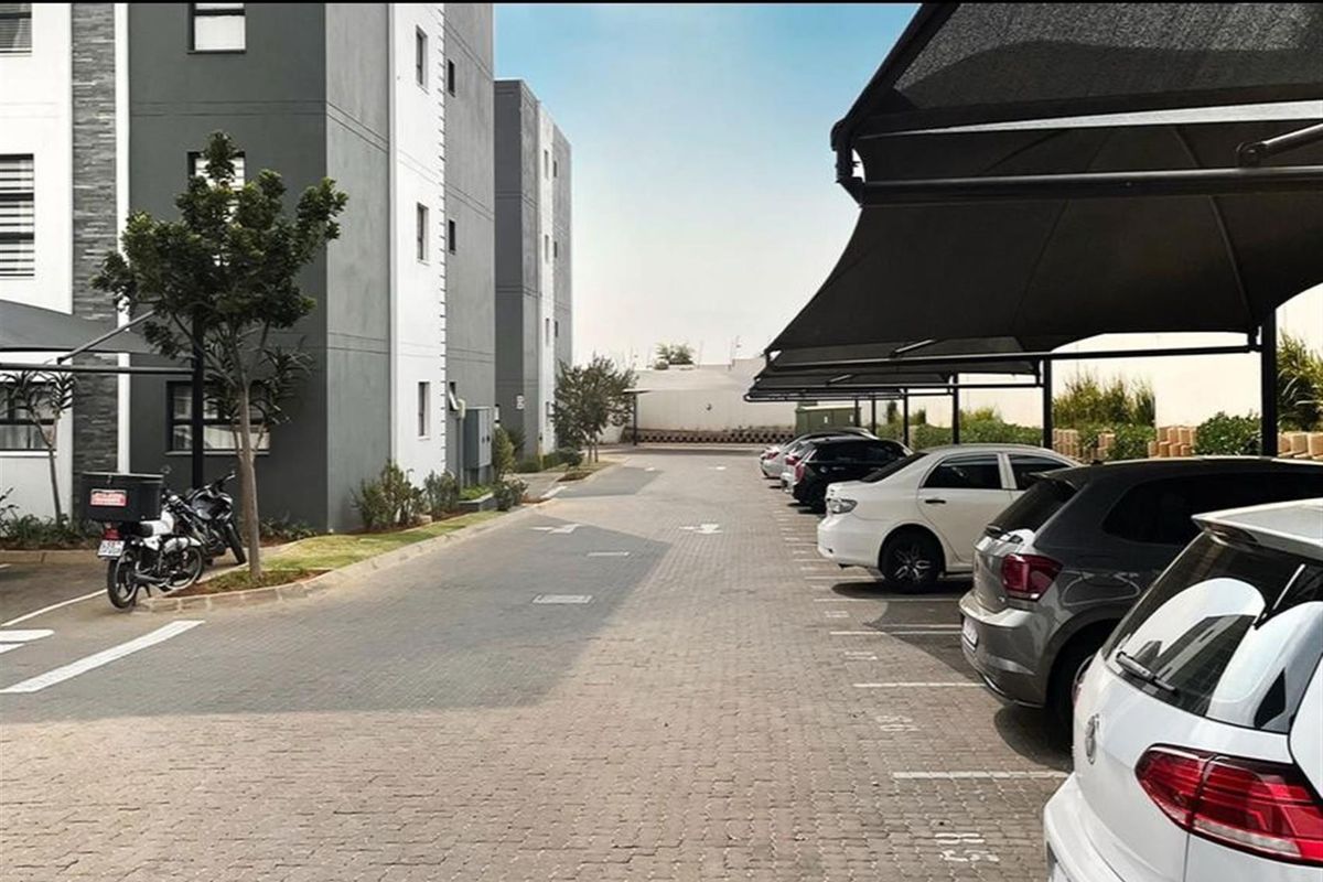 Exterior view of the apartment complex parking area featuring paved driveways and covered parking bays for residents.