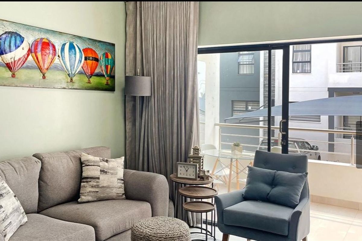 A bright living room featuring large sliding glass doors that open onto a private balcony, providing natural light and outdoor access.