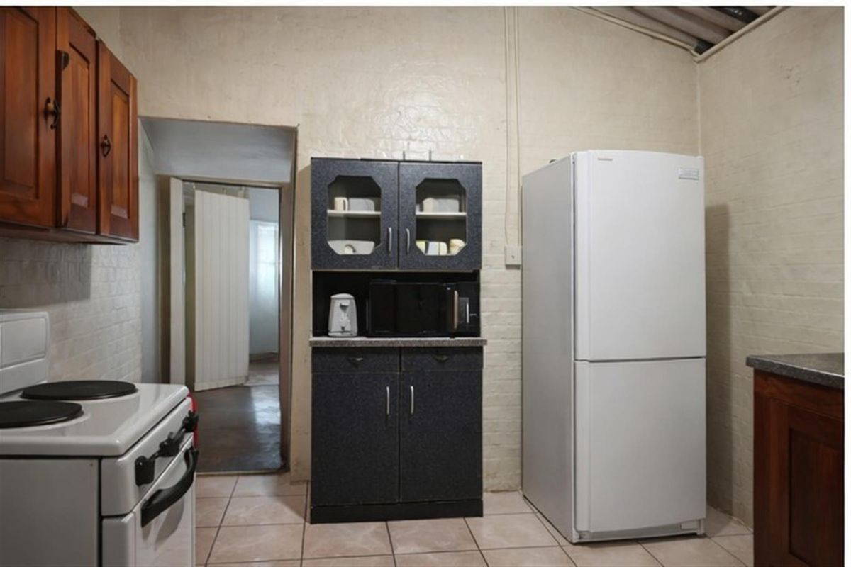 A functional kitchen area featuring tiled flooring, built-in cabinetry, and a freestanding stove, providing a practical space for meal preparation.