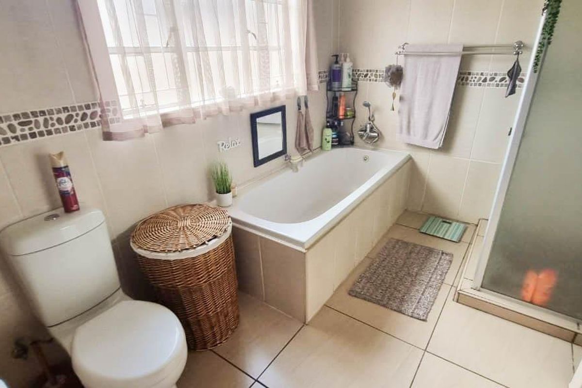 A functional bathroom featuring a built-in bathtub, separate shower enclosure, tiled walls, and floor, providing a practical layout for daily use.