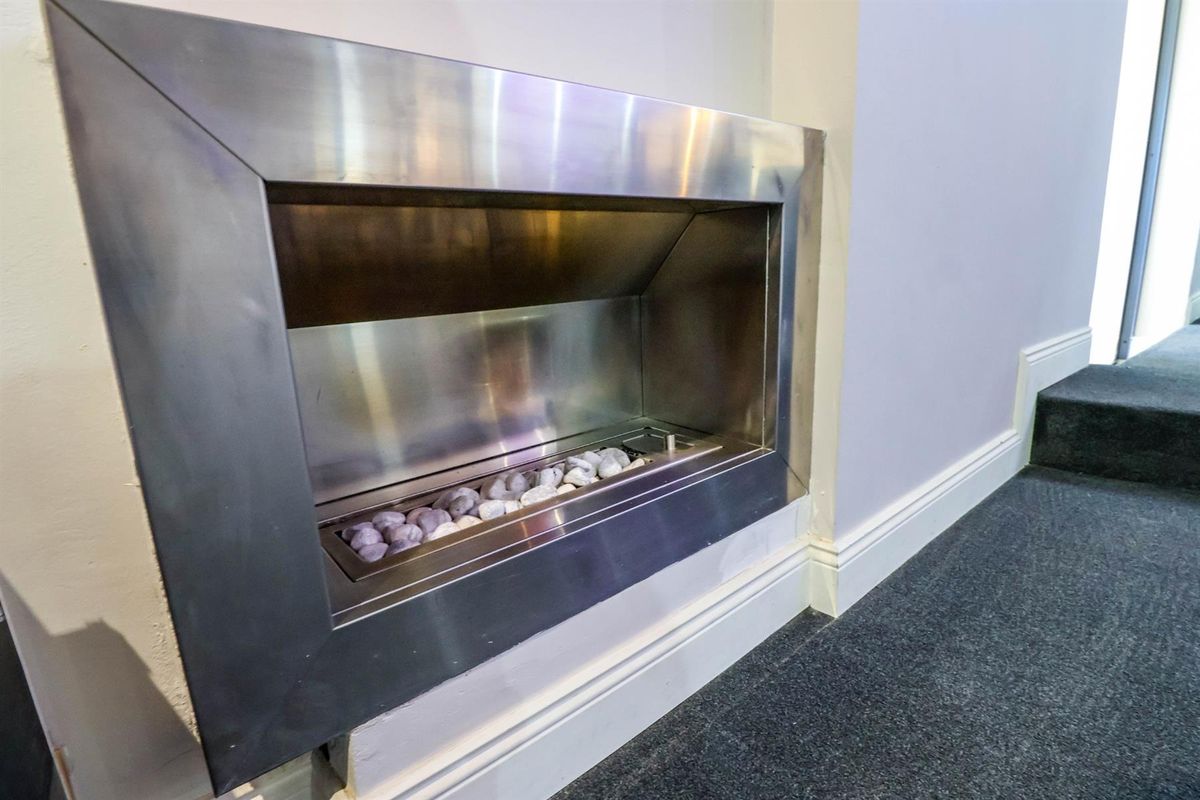 A modern, built-in stainless steel fireplace feature set into a wall, adding a contemporary focal point to the living space.