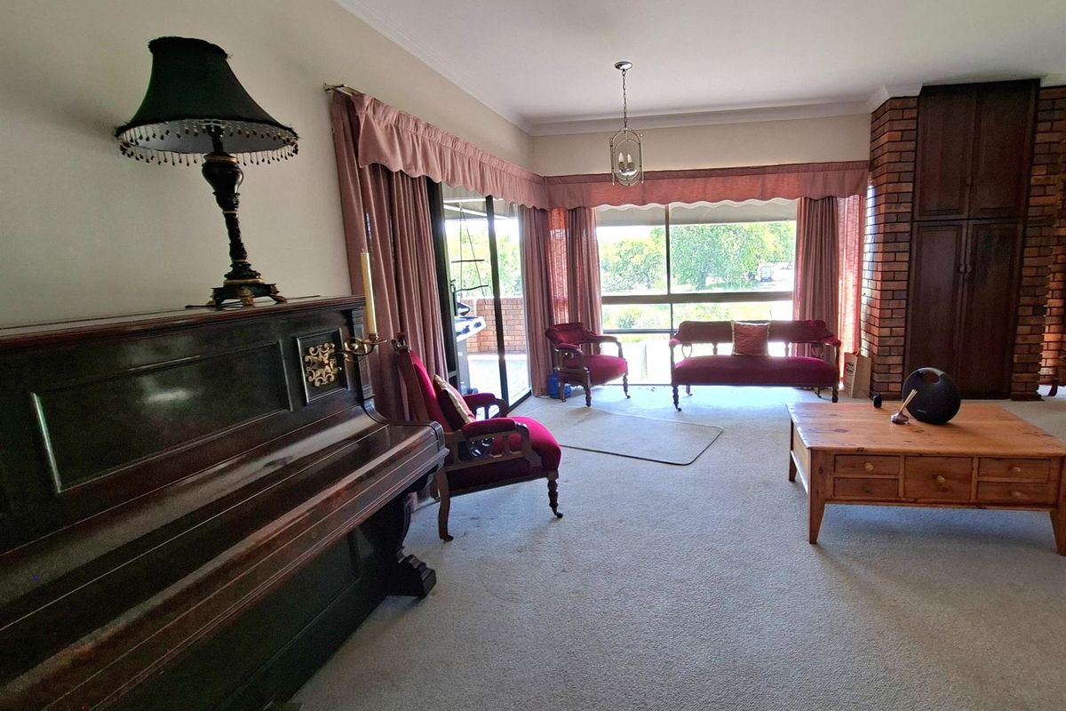 Spacious living room featuring a prominent brick fireplace, large windows with natural light, and direct access to an outdoor patio area.