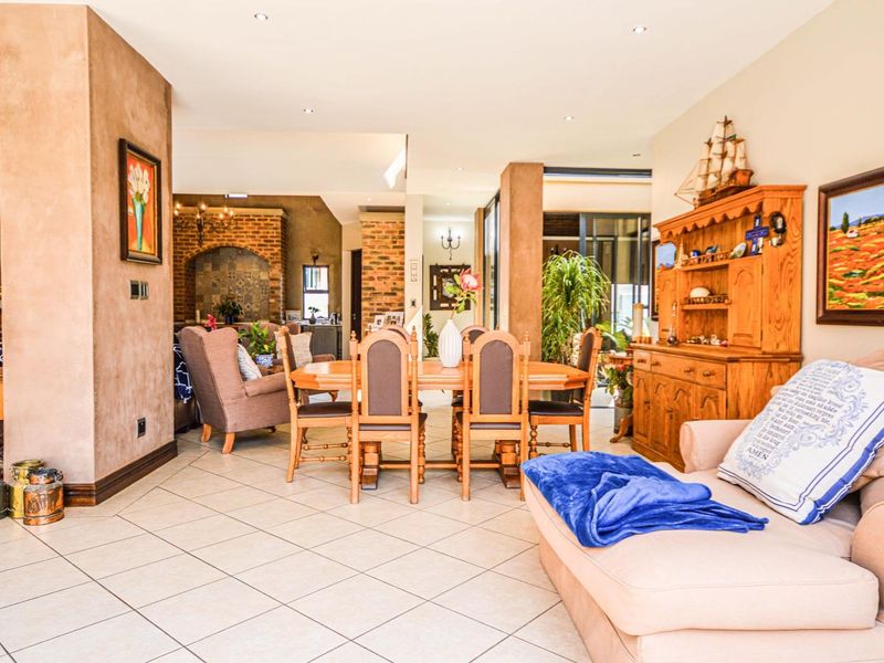 Spacious open-plan living and dining area featuring tiled floors, recessed lighting, and a distinctive exposed brick feature wall.