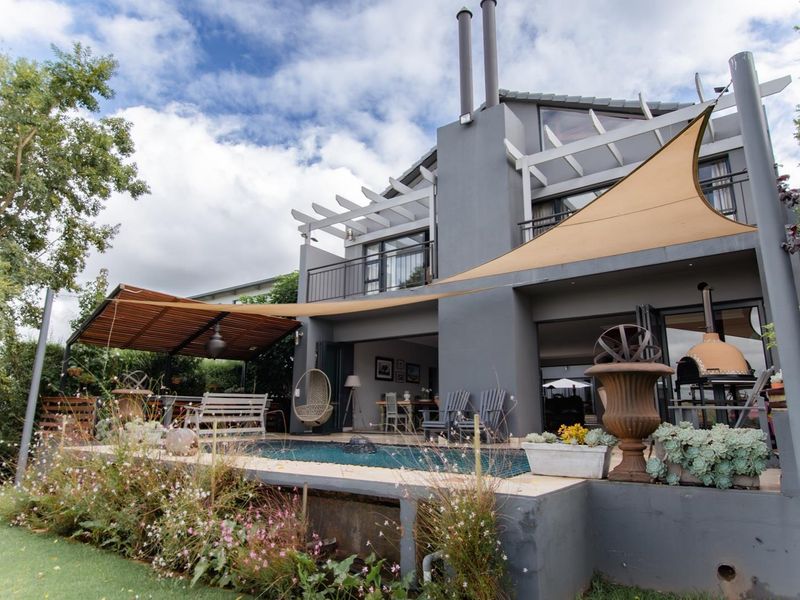 Rear view of the house featuring a swimming pool, covered patio area with a pergola, balcony, and an outdoor pizza oven.