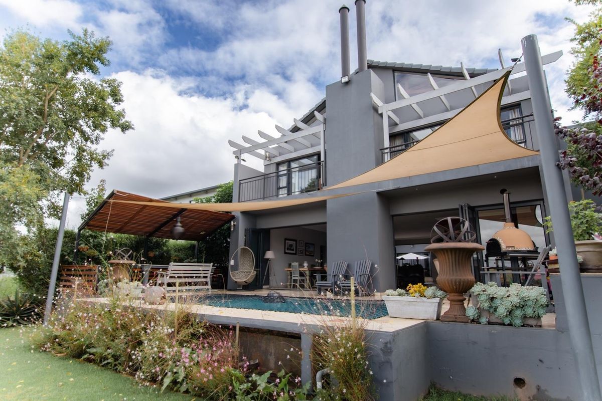 Rear view of the house featuring a swimming pool, covered patio area with a pergola, balcony, and an outdoor pizza oven.
