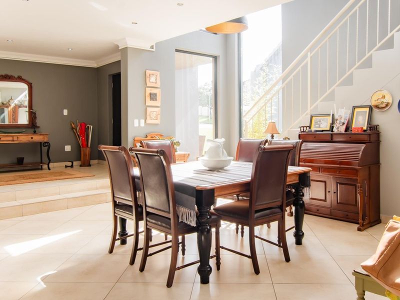 Spacious dining area featuring tiled flooring, recessed lighting, and a modern staircase, with large windows providing ample natural light.