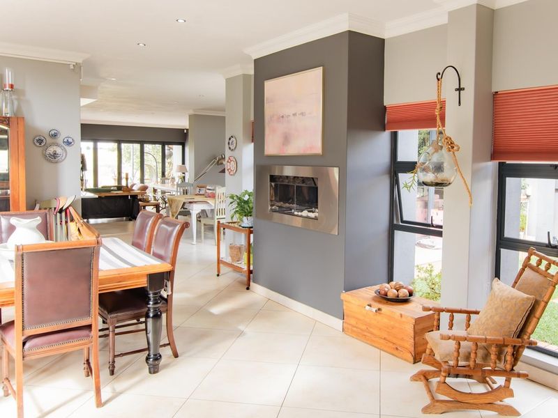 Spacious open-plan living and dining area featuring a modern built-in fireplace, tiled flooring, and large windows providing ample natural light.
