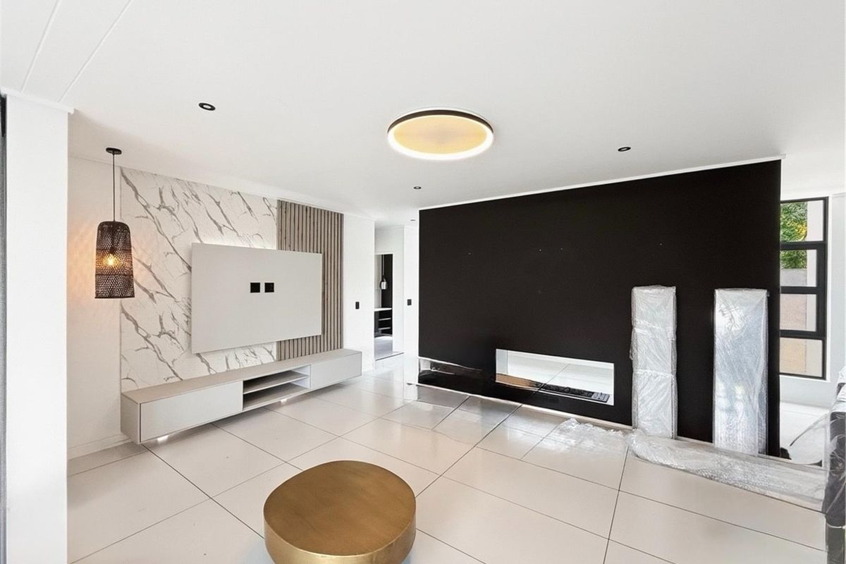 Modern living room featuring a sleek marble-look feature wall, built-in media cabinetry, a contemporary fireplace, and large format floor tiles.