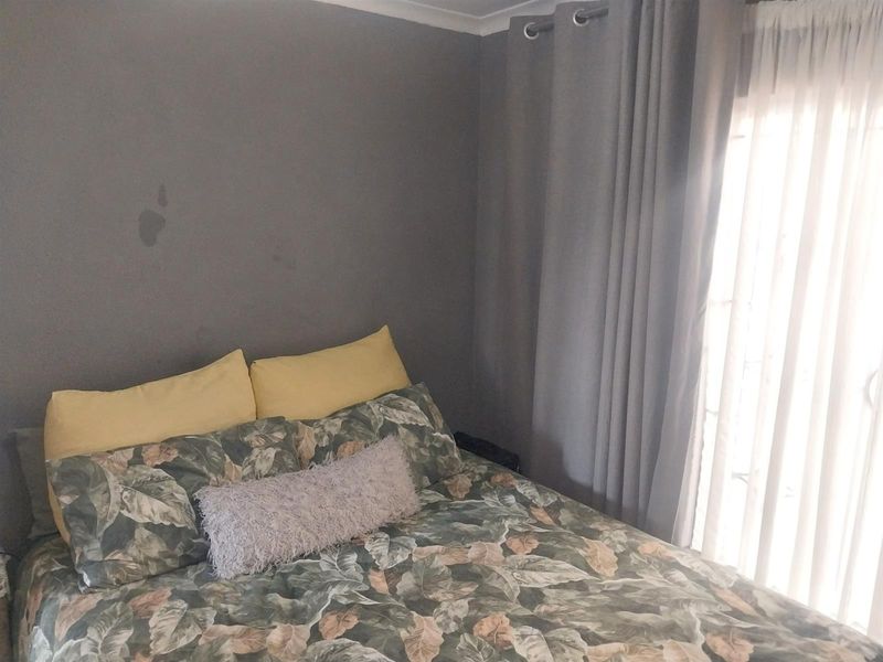 A bedroom featuring grey painted walls, a sliding door with curtains, and neutral flooring.