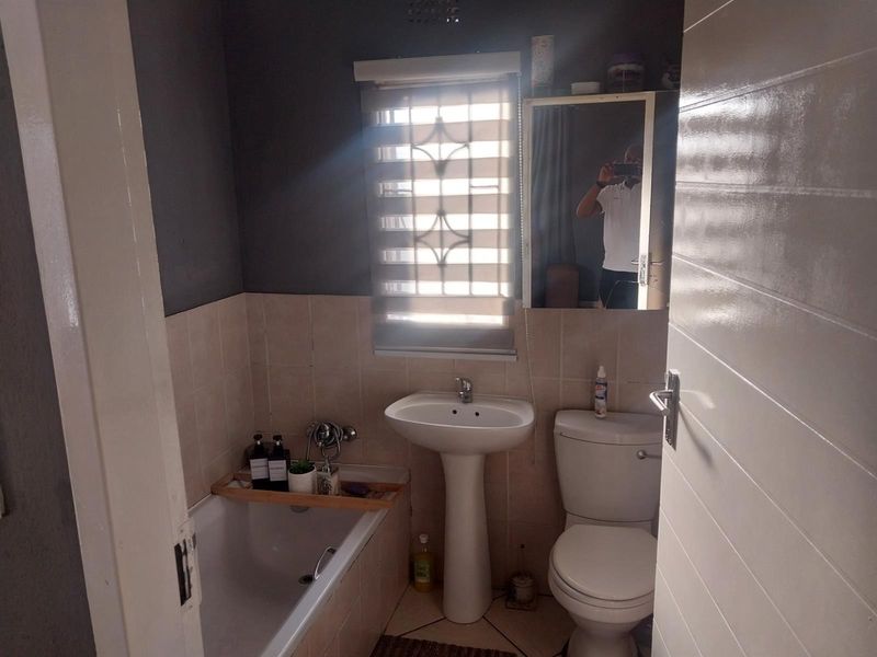 A compact bathroom featuring a pedestal basin, a standard toilet, and a bathtub with tiled surround.