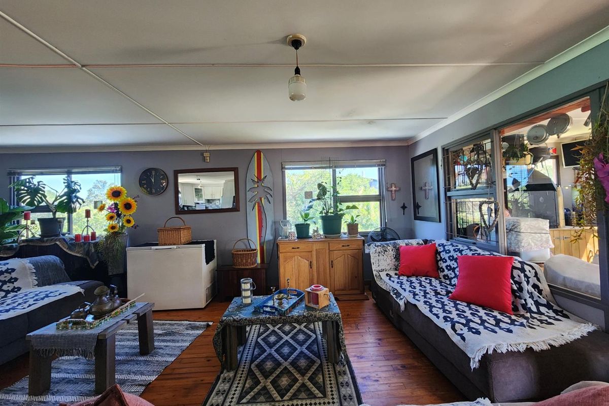 A spacious living room featuring timber flooring, large windows, and a neutral wall finish, offering a comfortable and functional living space.