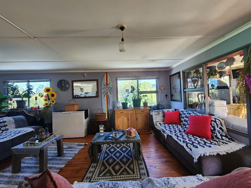 A spacious living room featuring timber flooring, large windows, and a neutral wall finish, offering a comfortable and functional living space.