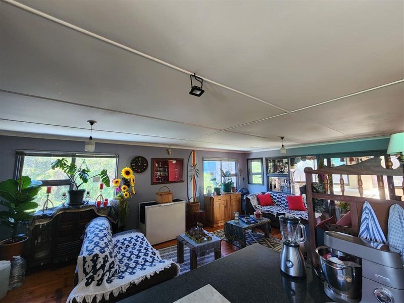 Open plan living area featuring timber flooring, large windows for natural light, and a functional layout connecting to the kitchen space.