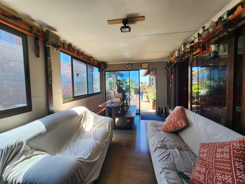 A sunroom or enclosed patio area featuring large windows, wood-look flooring, and direct access to the outdoor deck.