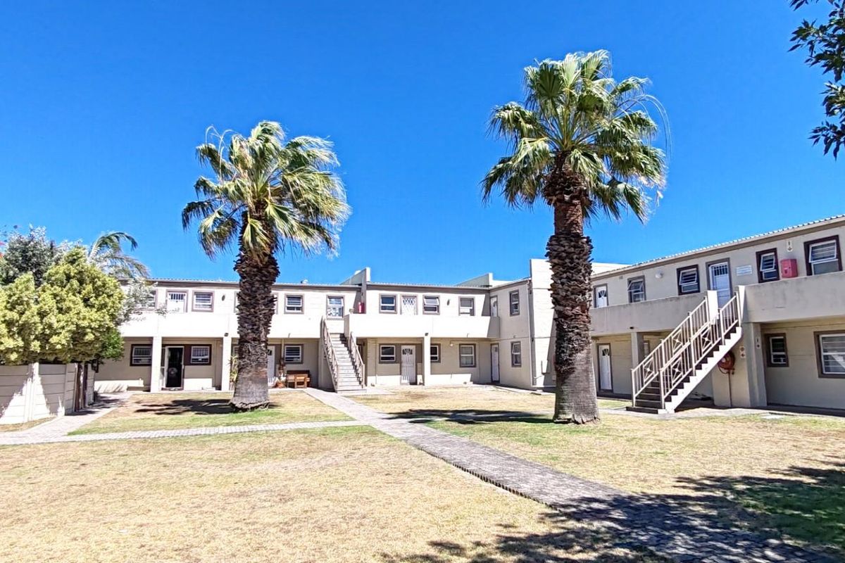 Exterior view of an apartment complex featuring a central courtyard, paved walkways, and external staircases providing access to upper-level units.
