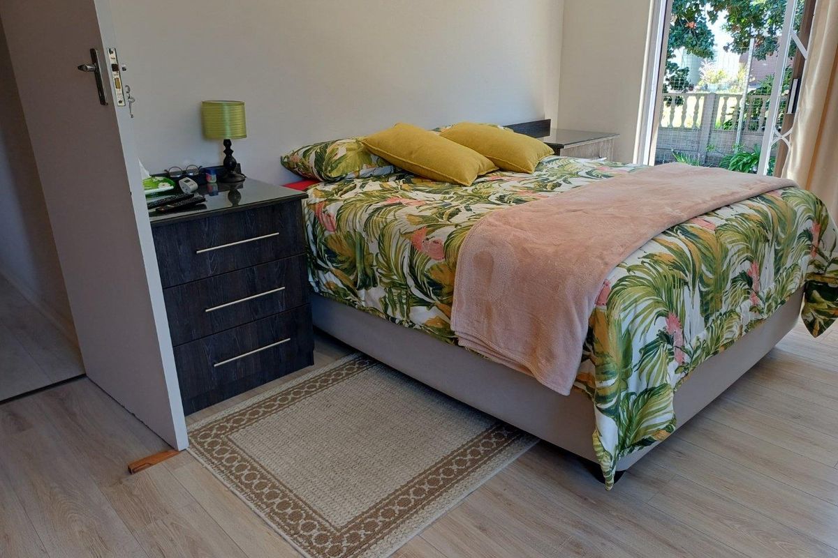 A well-lit bedroom featuring light wood-look flooring and a sliding glass door providing direct access to the outdoor area.