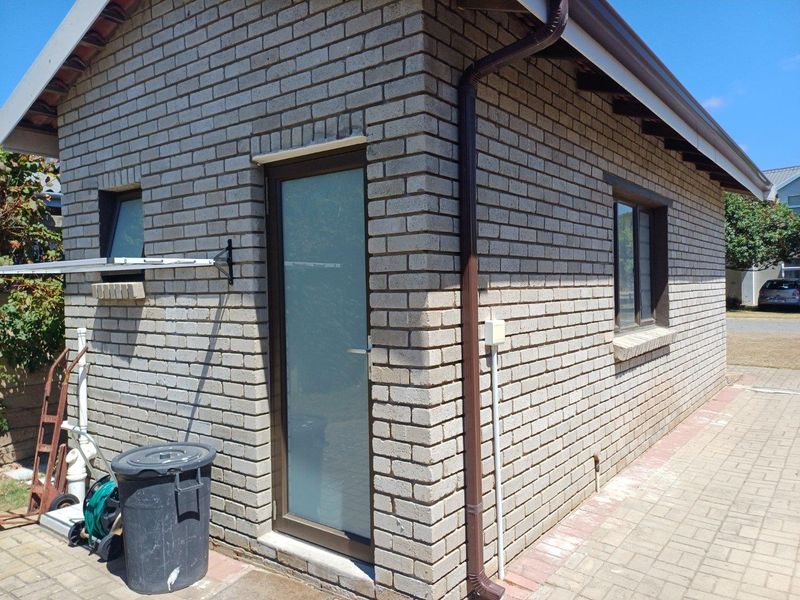 Exterior view of the side elevation featuring face brick construction, aluminium window frames, and a single access door with frosted glass.