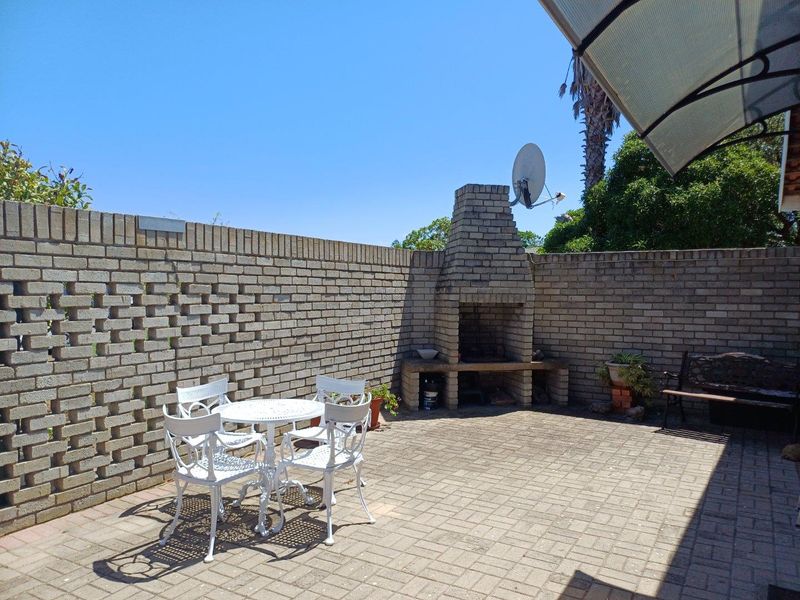 Outdoor patio area featuring a built-in brick braai or fireplace, enclosed by a decorative brick boundary wall and paved flooring.