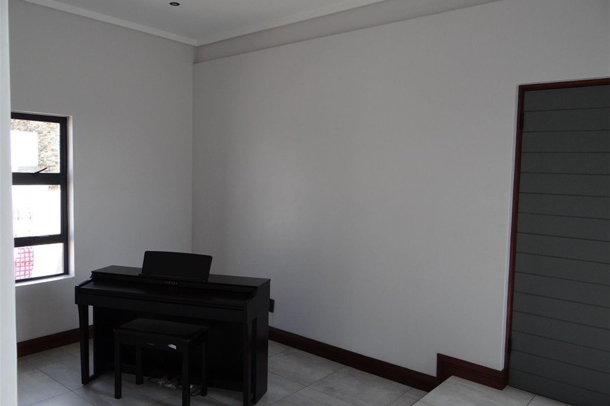 A neutral, well-lit room featuring tiled flooring, a modern window, and a dark-toned interior door.