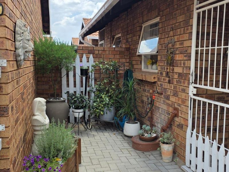 A private paved courtyard entrance featuring face-brick walls, a security gate, and an outdoor water tap.