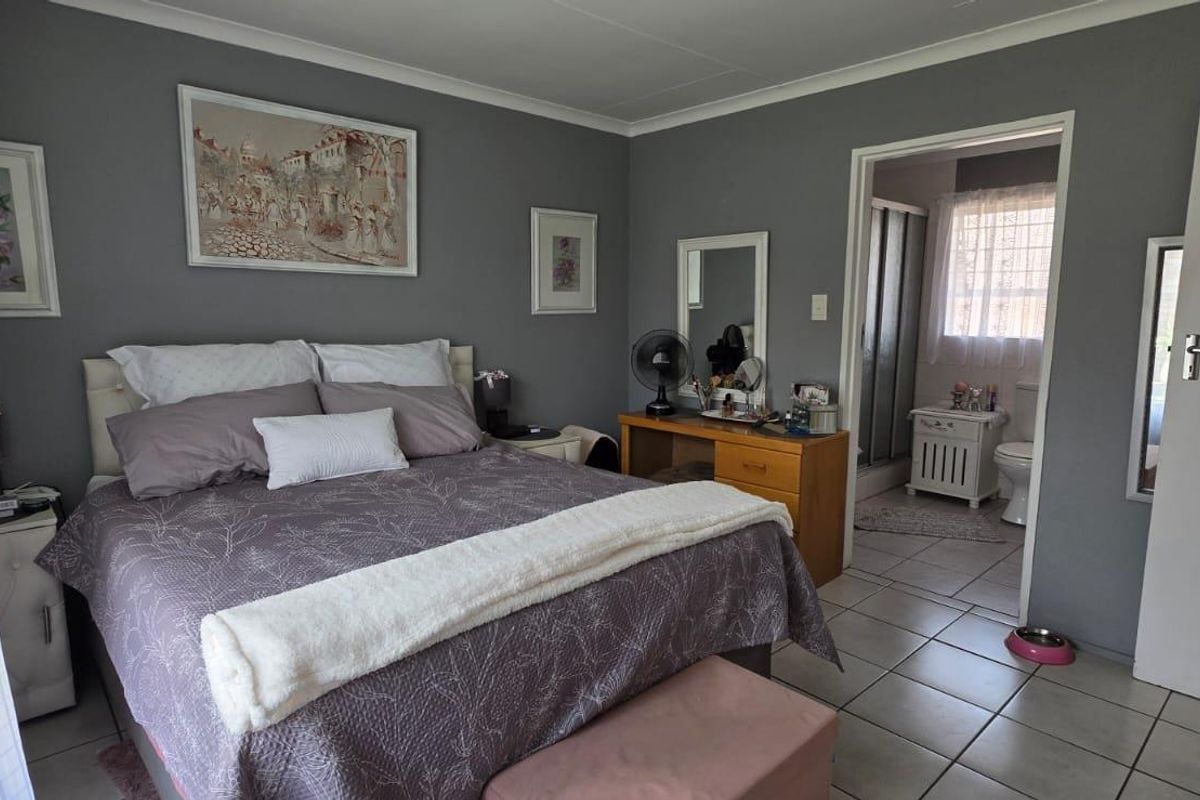 A bedroom featuring tiled flooring and an en-suite bathroom, providing a functional layout with neutral wall tones.
