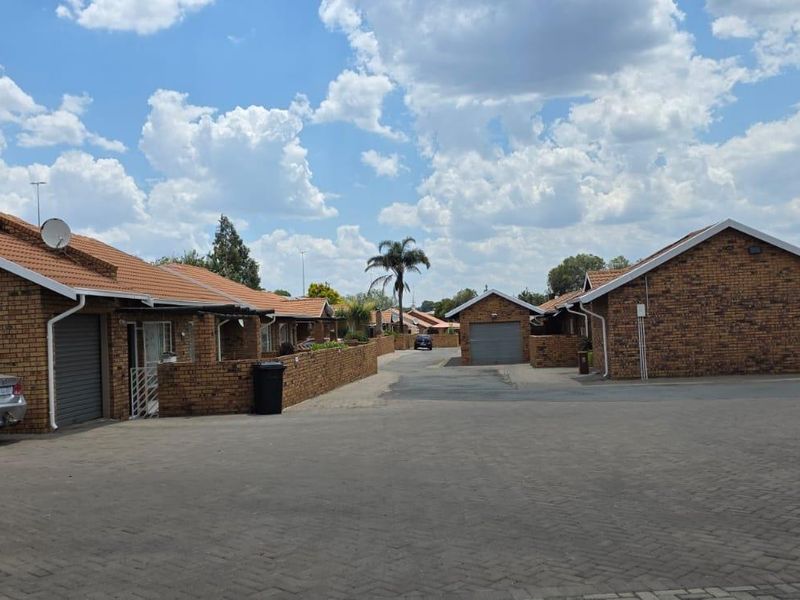 Exterior view of a residential apartment complex featuring face-brick facades, tiled roofs, and paved communal driveway areas.
