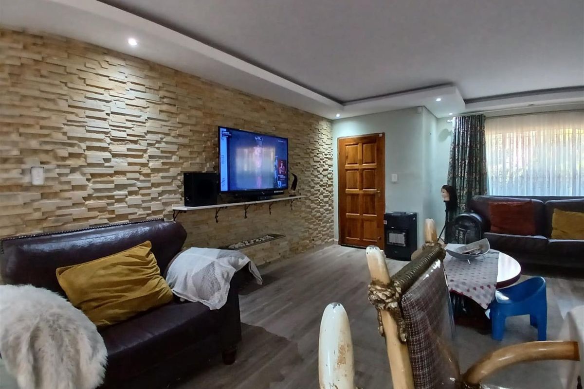 Living room featuring a textured stone feature wall, recessed ceiling lighting, and wood-look flooring.