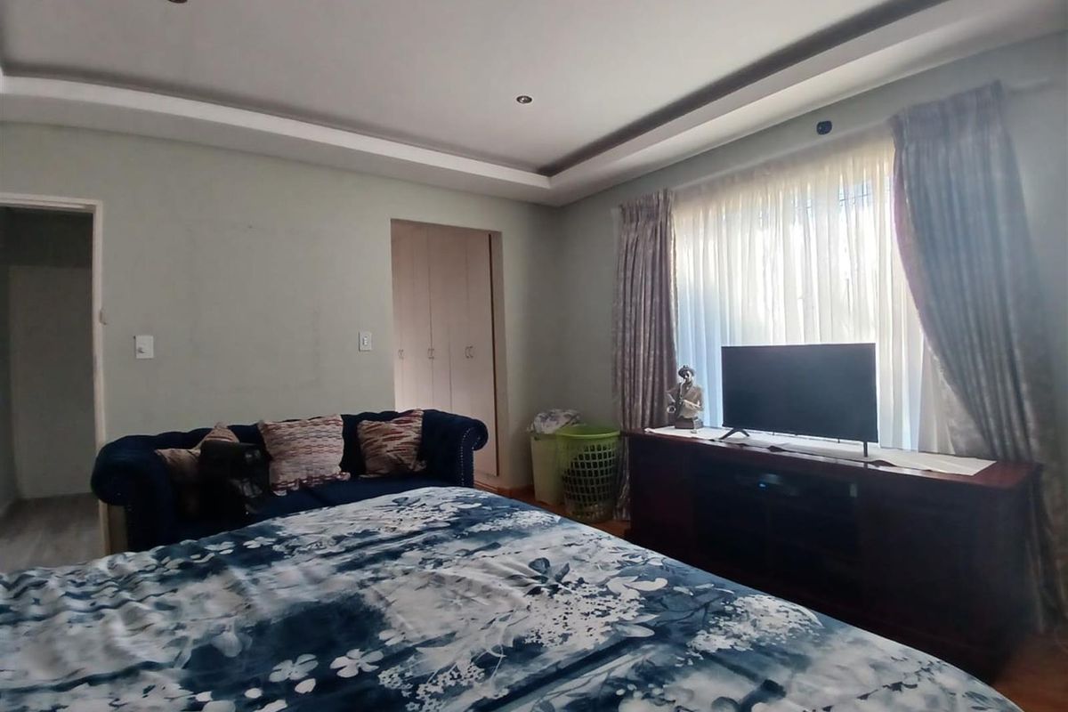 A spacious bedroom featuring recessed ceiling lighting, built-in cupboards, and large windows with curtain tracks.