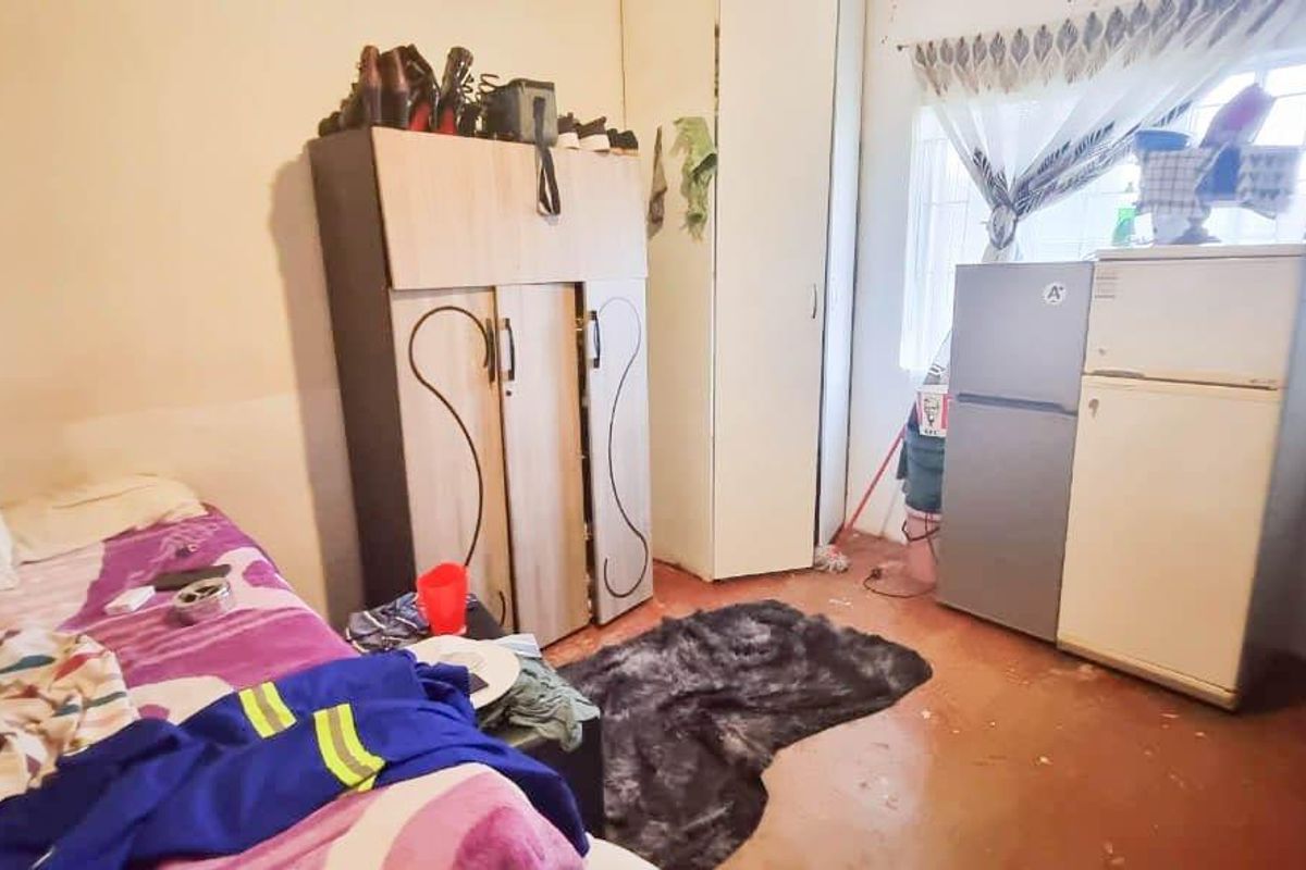 A bedroom featuring built-in wardrobe storage and security bars on the window, requiring cosmetic updates to improve the overall finish and appeal.