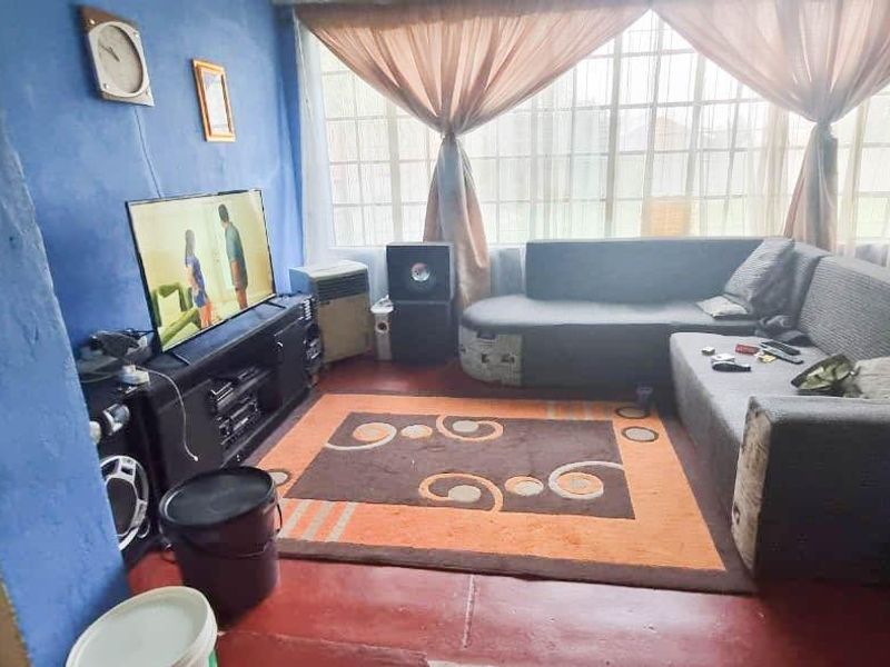 A living room featuring a large window and painted concrete flooring, currently requiring cosmetic updates to improve the overall aesthetic and finish.