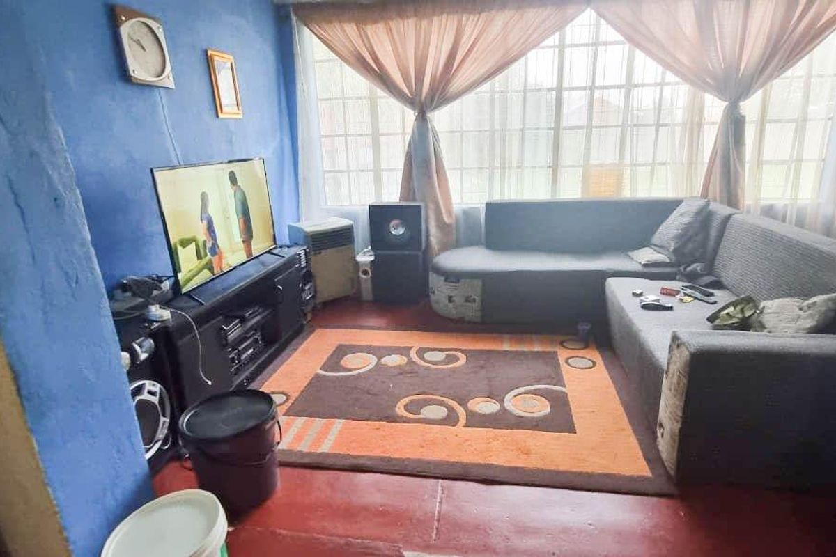 A living room featuring a large window and painted concrete flooring, currently requiring cosmetic updates to improve the overall aesthetic and finish.
