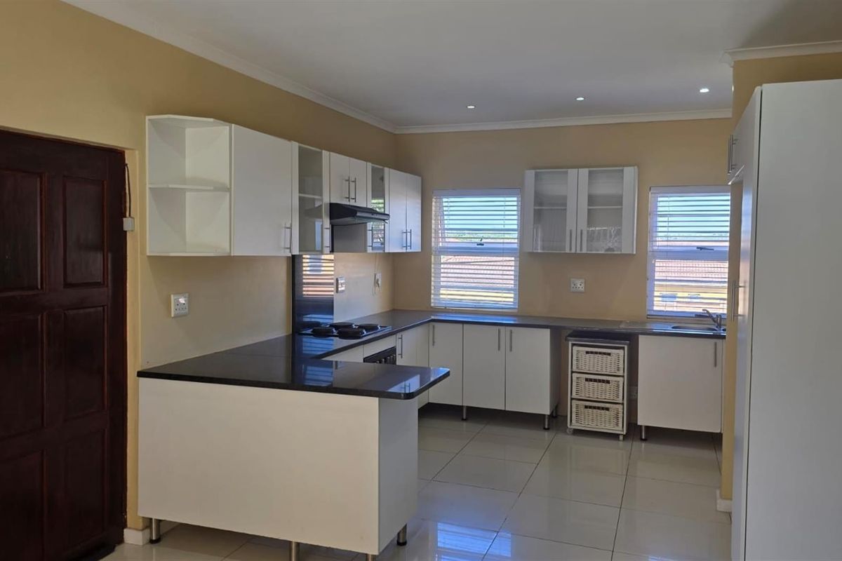 A functional kitchen featuring white cabinetry, dark countertops, tiled flooring, and built-in cooking appliances, offering a clean and practical workspace.