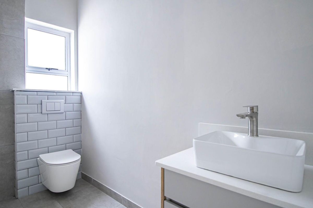 Modern bathroom featuring a wall-mounted toilet with concealed cistern, subway tile backsplash, and a contemporary vessel sink vanity.