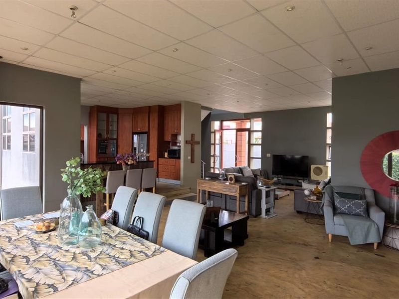 Spacious open-plan living and dining area featuring a wood-burning fireplace, integrated kitchen cabinetry, and large glass doors leading to the garden.