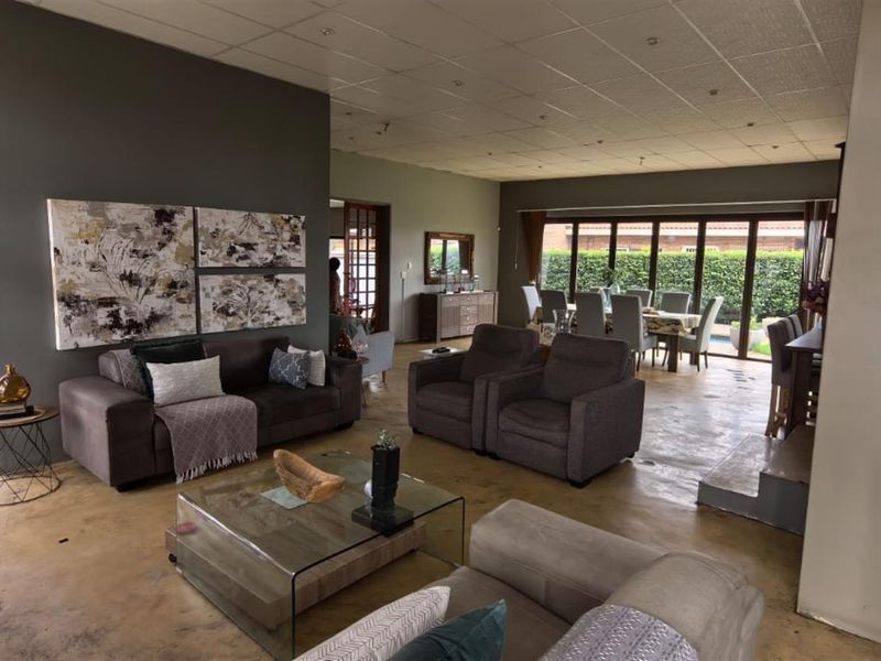 Spacious open-plan living and dining area featuring polished concrete floors, large glass sliding doors, and a suspended ceiling, offering a bright and versatile layout.