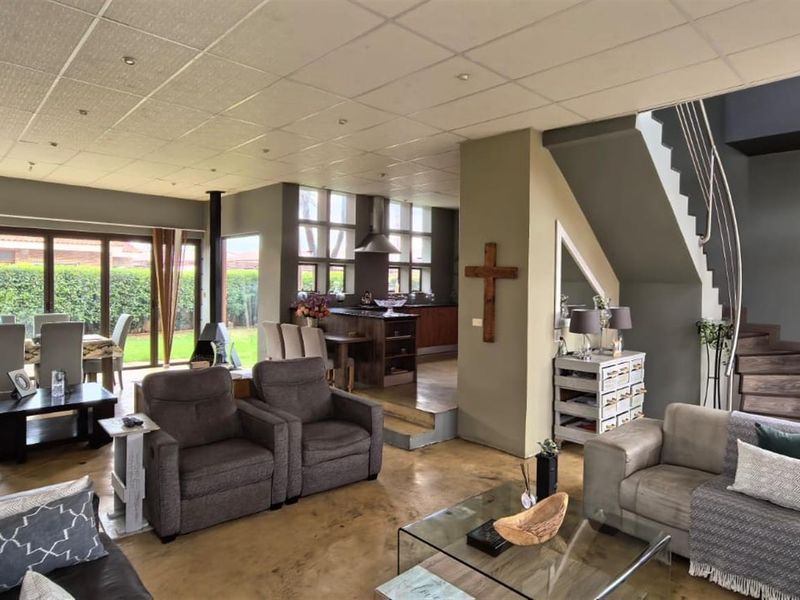 Spacious open-plan living area featuring hardwood floors, a modern staircase, a fireplace, and seamless access to the garden through large sliding glass doors.