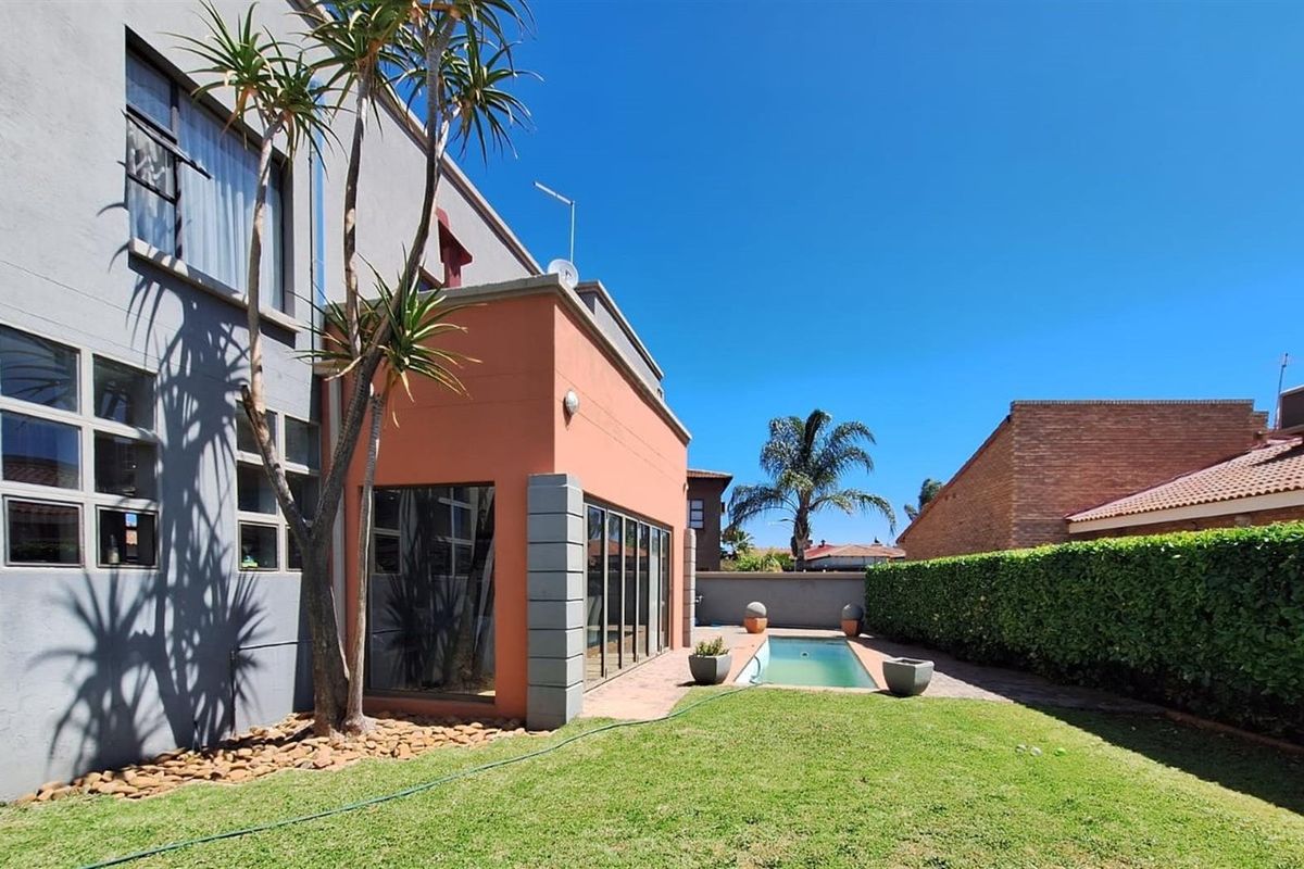 Rear exterior view featuring a private swimming pool, paved patio area, and well-maintained garden with established hedge boundaries.
