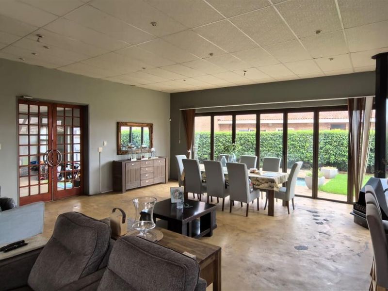 Spacious open-plan living and dining area featuring polished concrete floors, a wood-burning fireplace, and large sliding doors opening to the garden.