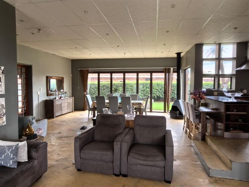 Spacious open-plan living, dining, and kitchen area featuring polished concrete floors, a modern fireplace, and large bi-fold doors opening to the garden.