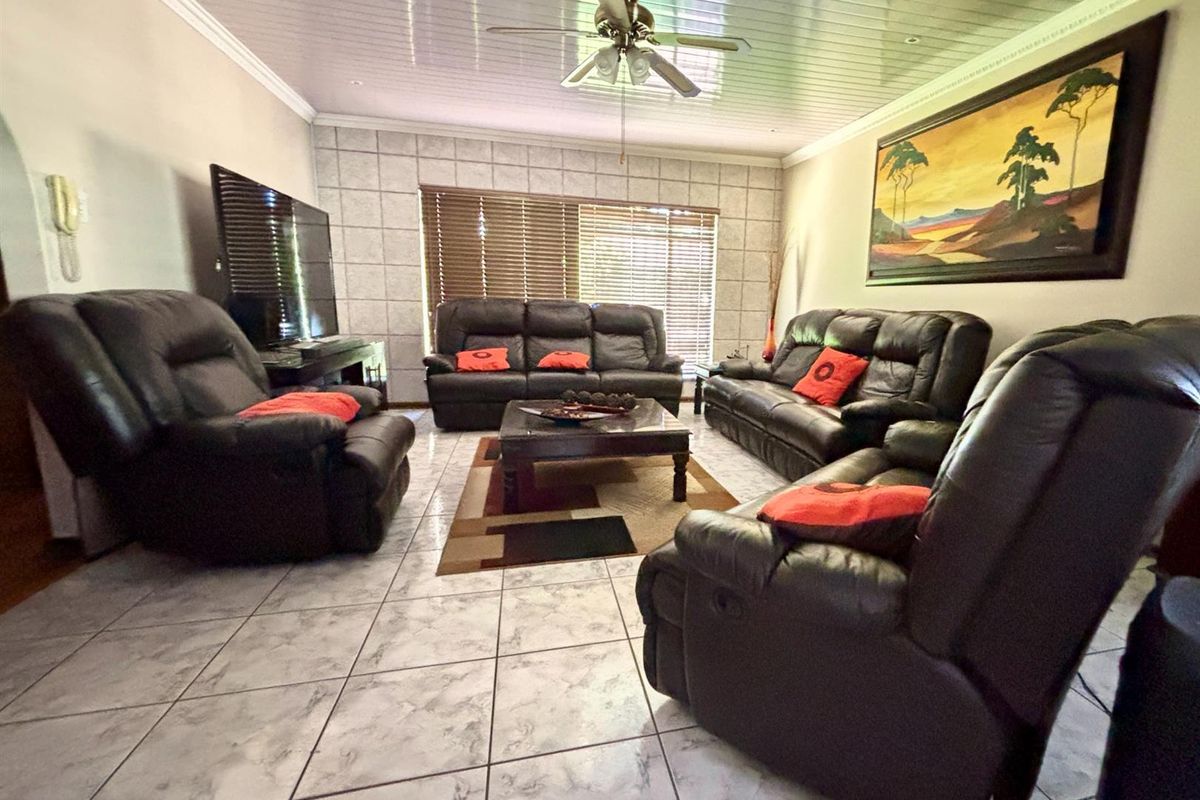 A living room featuring tiled flooring, a ceiling fan, and a tiled feature wall with window blinds.