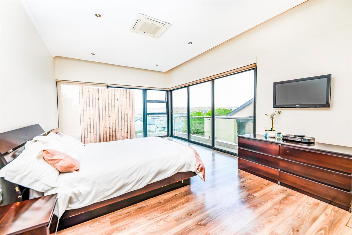 Spacious bedroom featuring large floor-to-ceiling sliding glass doors that open to a balcony, providing ample natural light and scenic views.