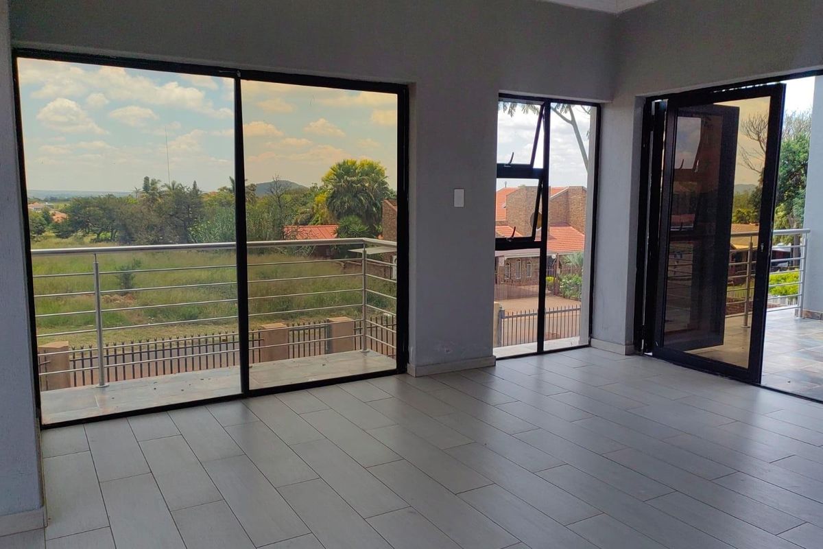 Bright and spacious living area featuring large sliding glass doors that open onto a balcony with scenic views and modern tiled flooring.