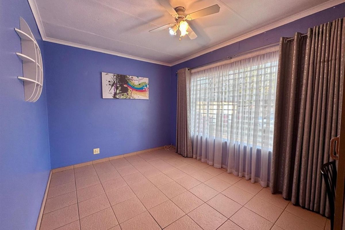 A bedroom featuring tiled flooring, a ceiling fan, and large windows with curtain tracks.