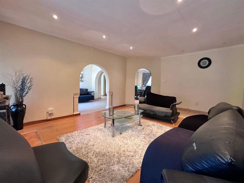 Spacious living room featuring arched doorways, recessed ceiling lighting, and warm-toned laminate flooring, creating an inviting and open atmosphere.