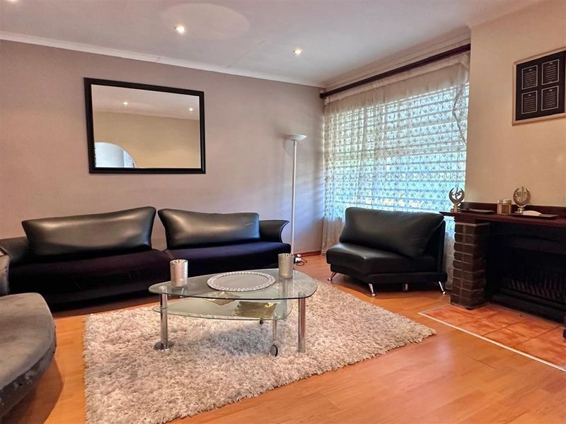 A comfortable living room featuring laminate flooring, a brick fireplace, and recessed ceiling lighting, creating a warm and inviting atmosphere.
