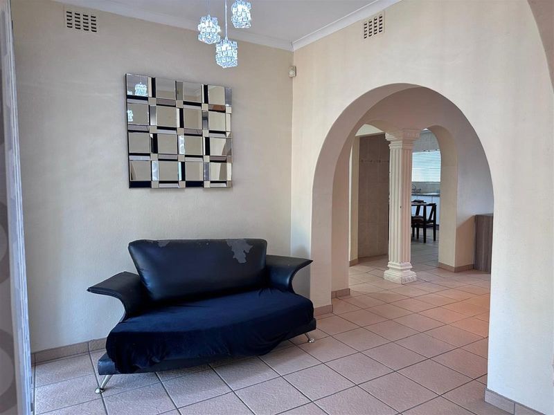 An entrance area featuring tiled flooring, decorative archways with a classical column, and recessed ceiling ventilation grilles.