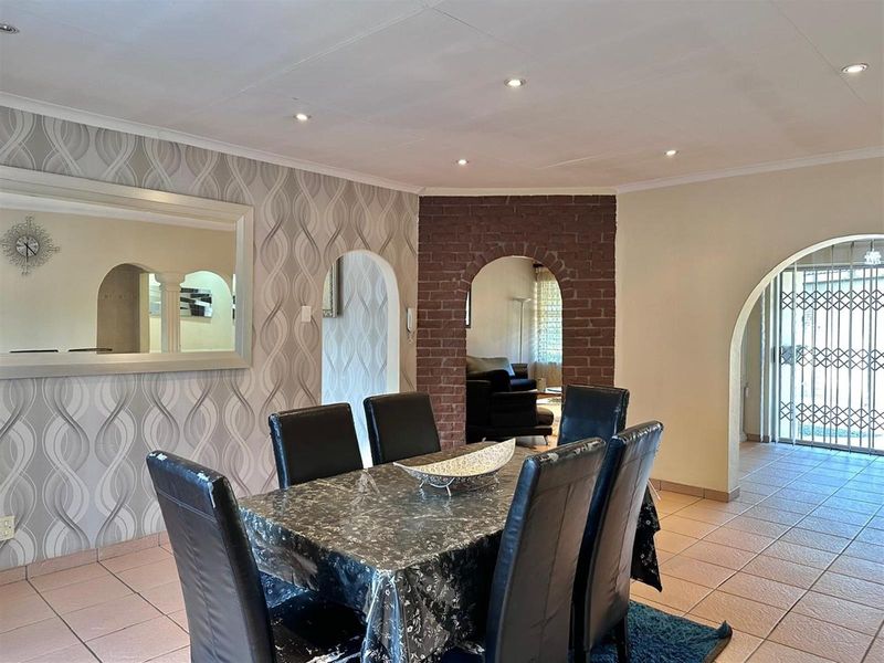 Dining area featuring tiled flooring, recessed ceiling lighting, and distinctive brick-accented archways connecting to adjacent living spaces.