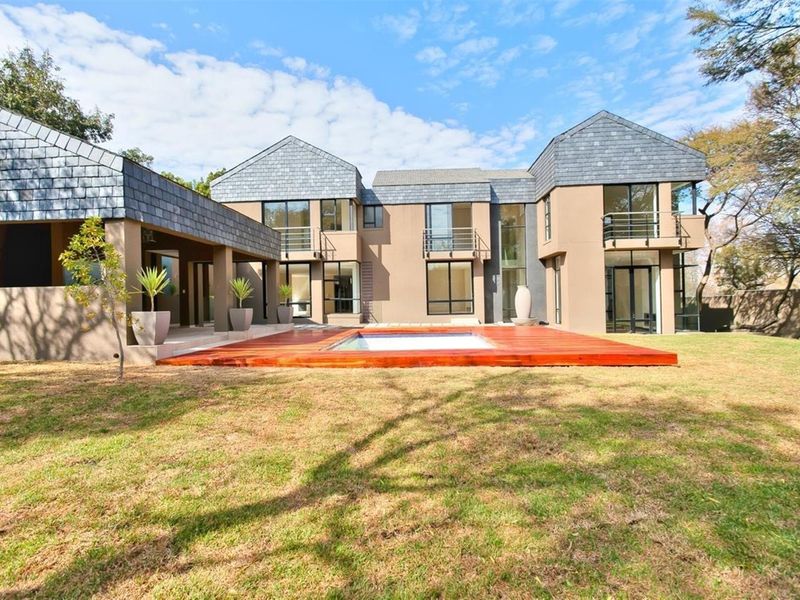 Rear view of a modern multi-level residence featuring a swimming pool with a timber deck, landscaped garden, and balconies.
